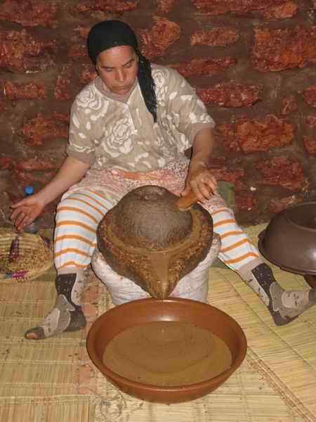 Woman grinding roasted argan kernels to culinary argan oil in morocco